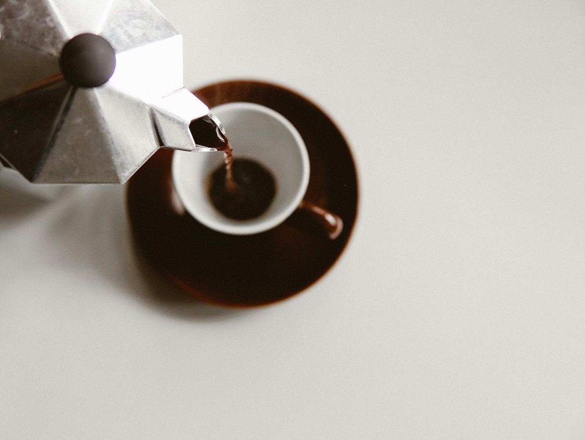 espresso being poured from a moka pot into a cup