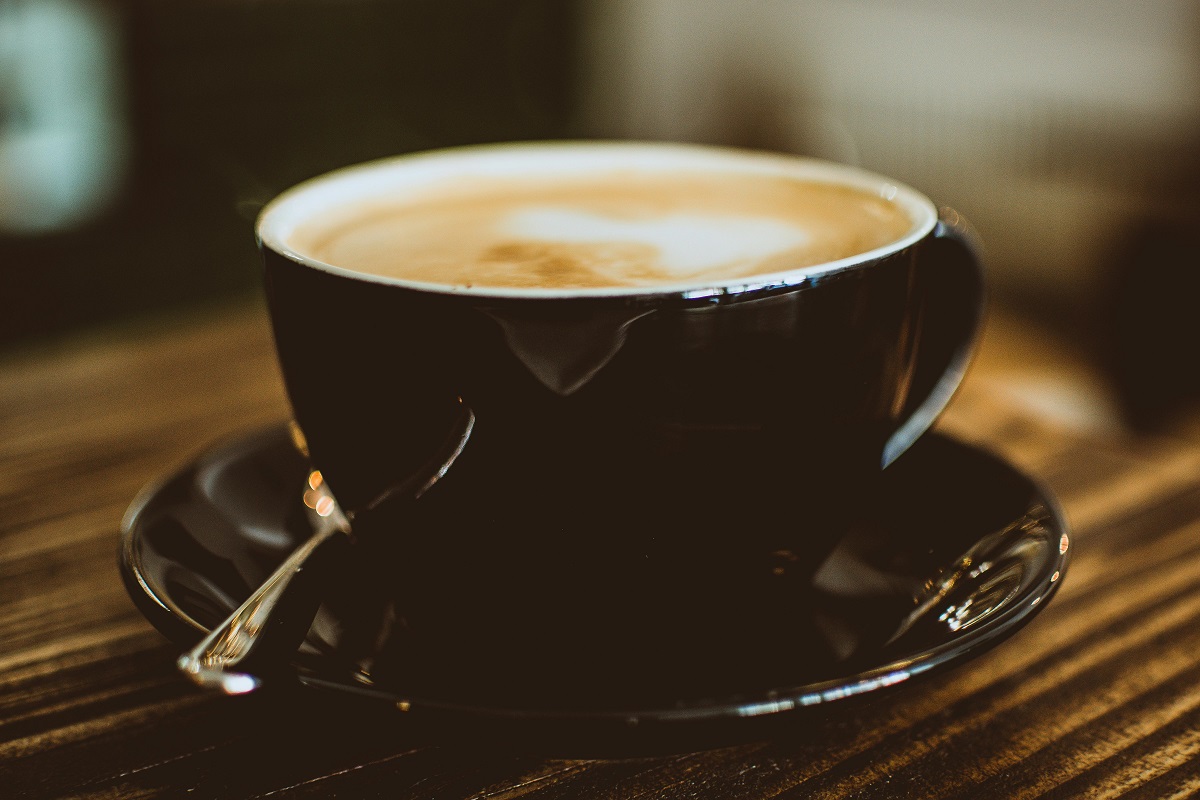 black cup with coffee and teaspoon on a black saucer