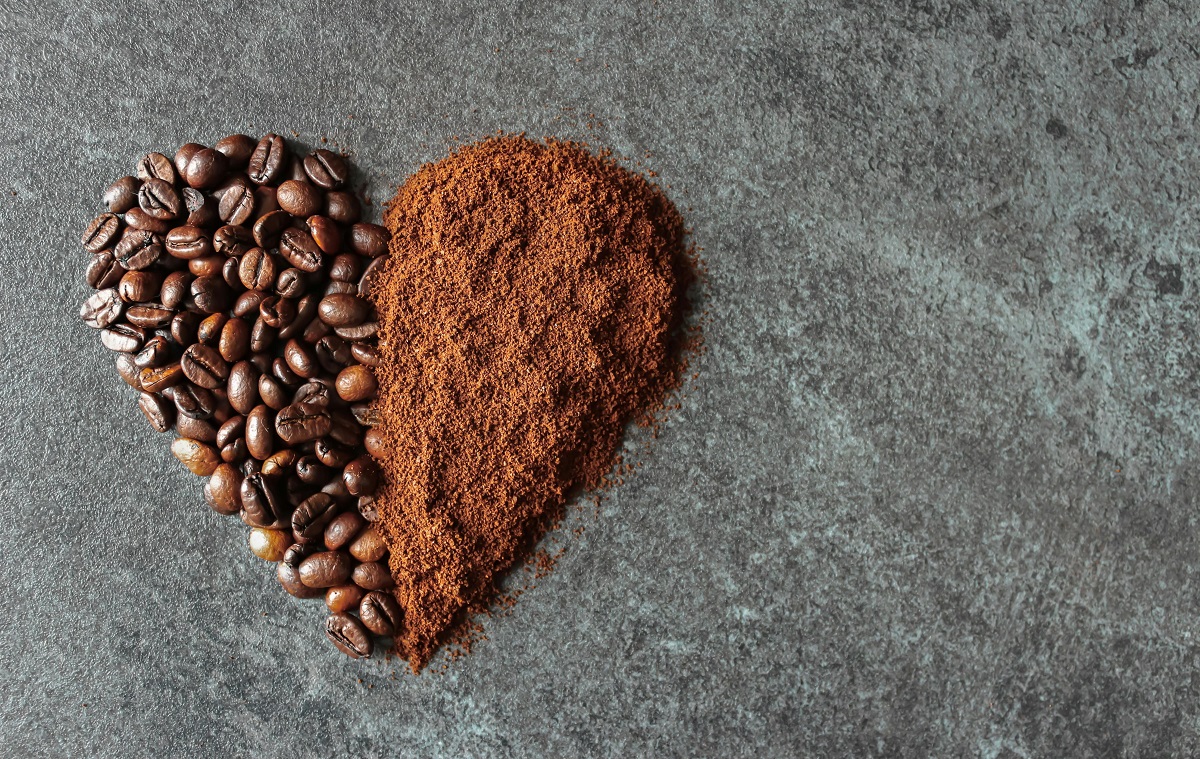 whole coffee beans and ground coffee forming a heart shape