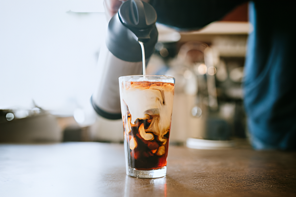 barista pouring milk into cold brew coffee