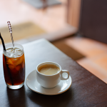 glass of cold brew coffee and cup of hot coffee on a wooden table