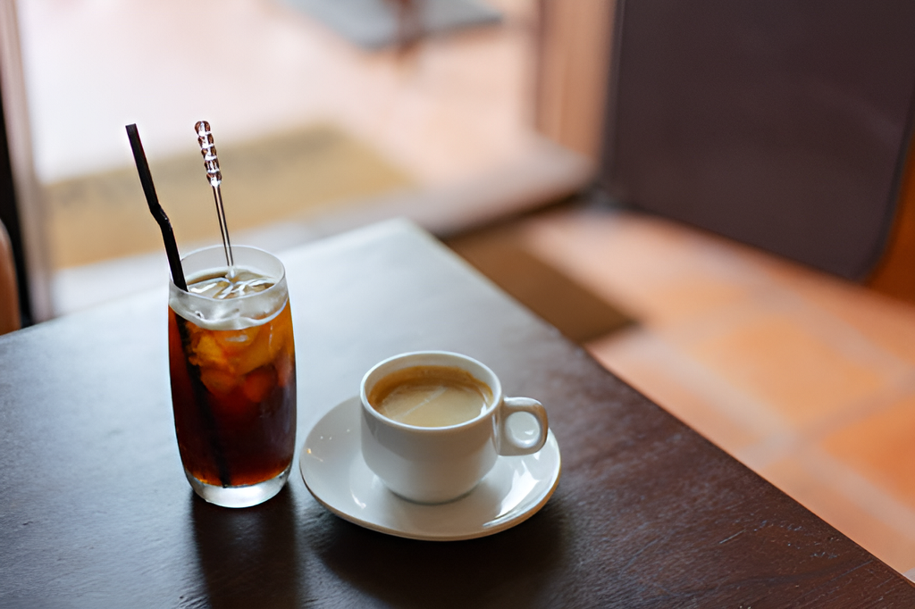 glass of cold brew coffee and cup of hot coffee on a wooden table