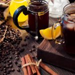 cold brew coffee in a mason jar and French press, surrounded by coffee beans and lemon slices
