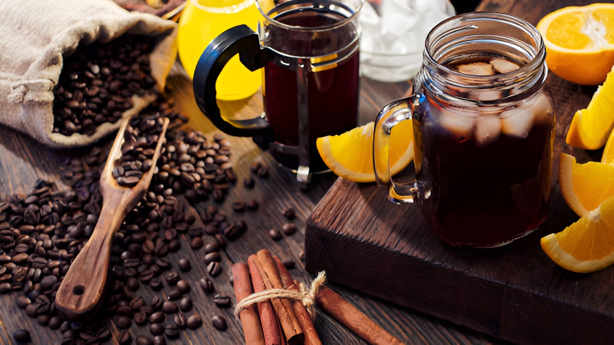 cold brew coffee in a mason jar and French press, surrounded by coffee beans and lemon slices